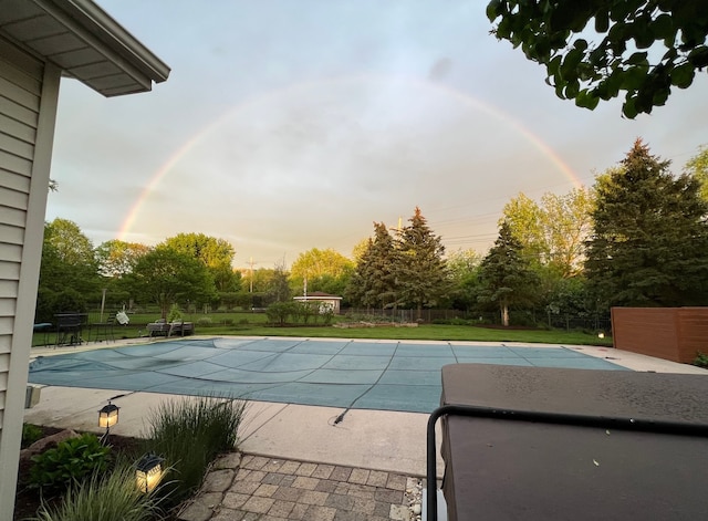 pool at dusk featuring a lawn