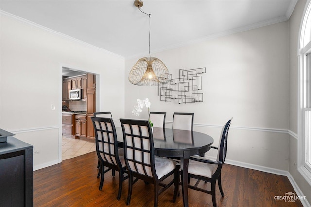 dining space with dark wood-type flooring, crown molding, and a chandelier