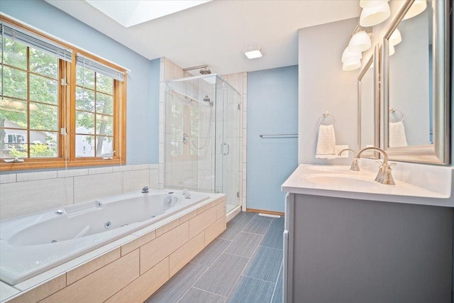 bathroom featuring tile patterned flooring, vanity, a skylight, and separate shower and tub