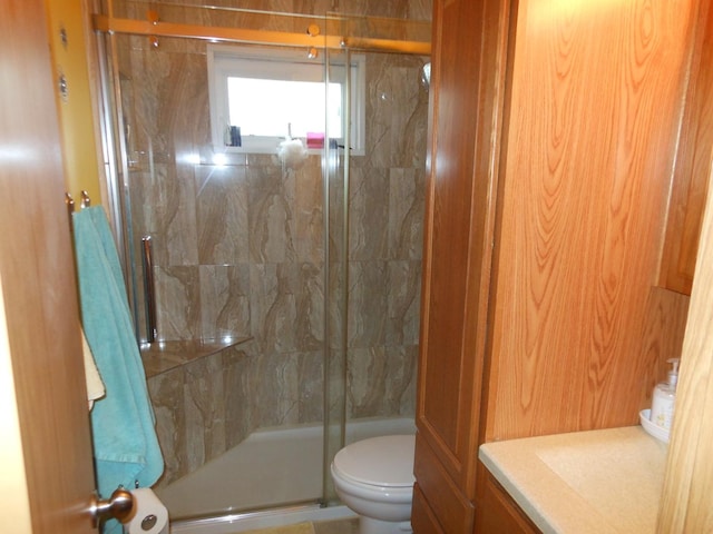 bathroom featuring toilet and a shower with shower door