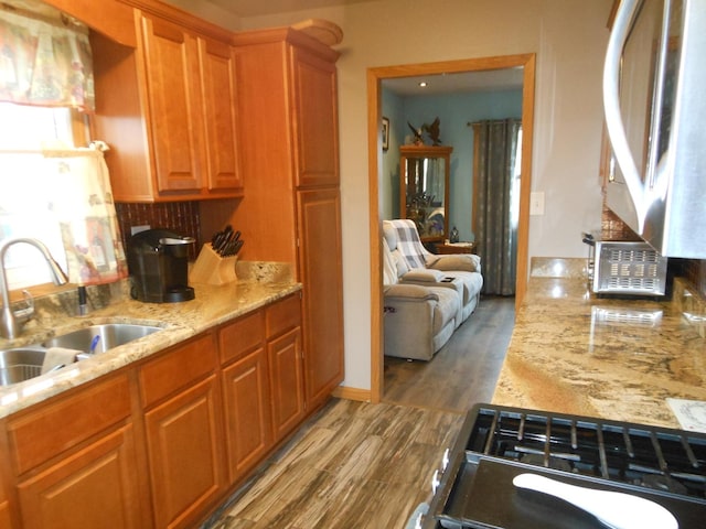 kitchen with light stone countertops, hardwood / wood-style floors, and sink