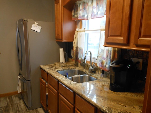 kitchen with hardwood / wood-style floors, light stone countertops, and sink