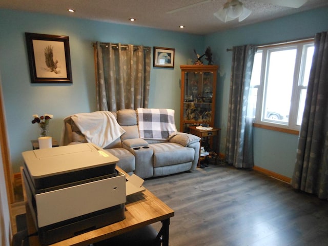 living area with wood-type flooring and ceiling fan