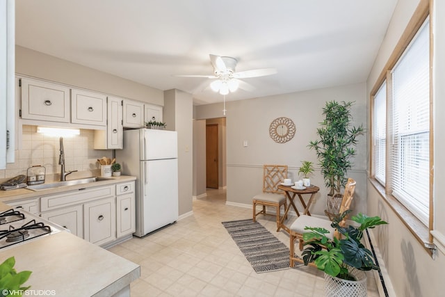 kitchen with decorative backsplash, white cabinetry, sink, and white fridge