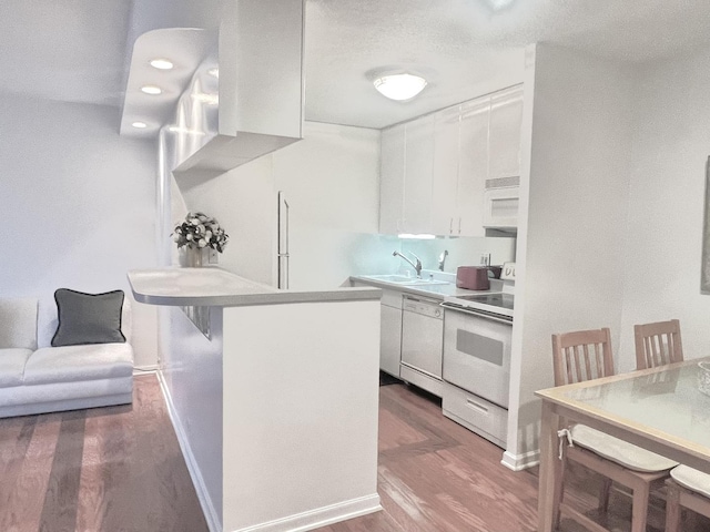 kitchen featuring sink, dark wood-type flooring, white appliances, a breakfast bar, and white cabinets