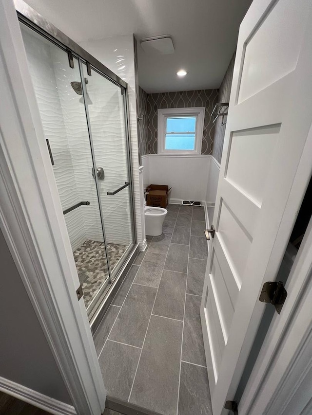 bathroom featuring tile patterned flooring, a shower with door, toilet, and a bidet