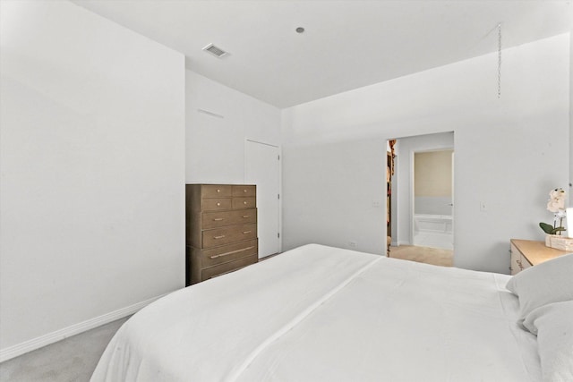 bedroom with light colored carpet and ensuite bath