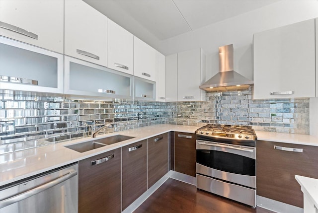 kitchen featuring dark brown cabinets, stainless steel appliances, white cabinetry, and wall chimney exhaust hood