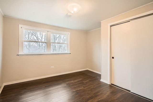 unfurnished bedroom with dark hardwood / wood-style flooring, a closet, and crown molding