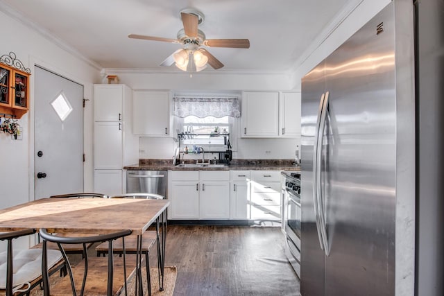 kitchen with sink, appliances with stainless steel finishes, dark hardwood / wood-style floors, dark stone counters, and white cabinets