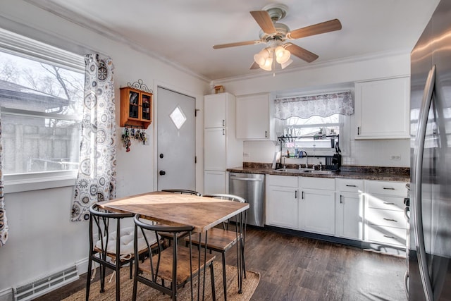 kitchen with sink, appliances with stainless steel finishes, dark stone countertops, white cabinets, and dark hardwood / wood-style flooring