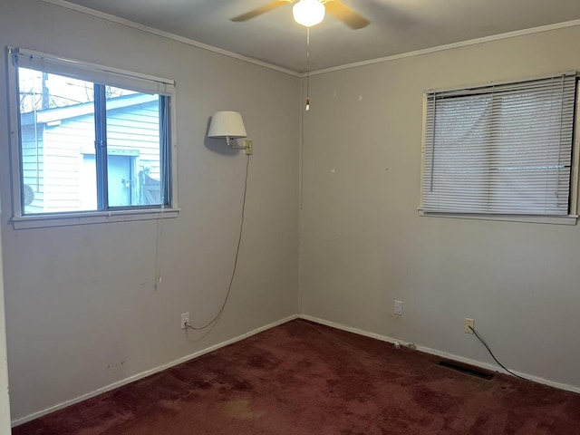 unfurnished room with dark colored carpet, ceiling fan, and crown molding