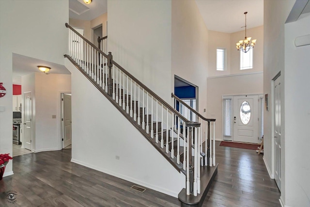 foyer entrance with baseboards, visible vents, stairway, wood finished floors, and a chandelier