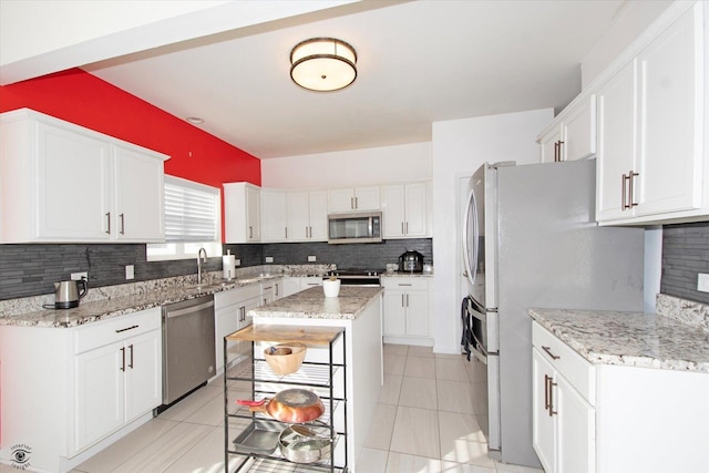 kitchen featuring stainless steel appliances, white cabinetry, a sink, and backsplash