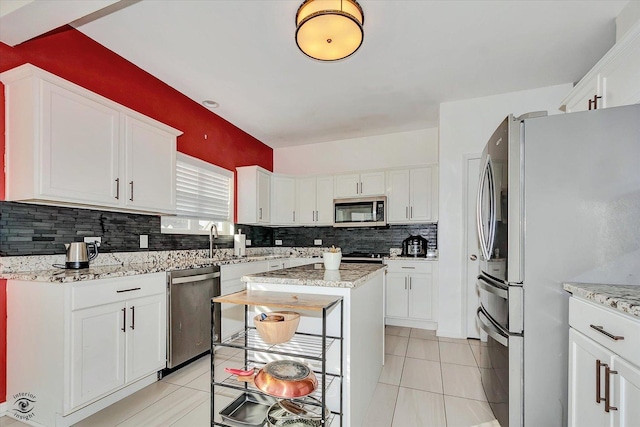 kitchen featuring light tile patterned floors, appliances with stainless steel finishes, decorative backsplash, and white cabinets