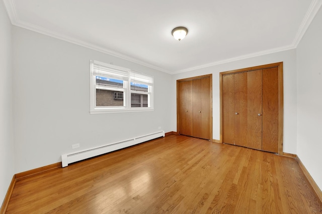 unfurnished bedroom featuring two closets, a baseboard radiator, light hardwood / wood-style flooring, and ornamental molding