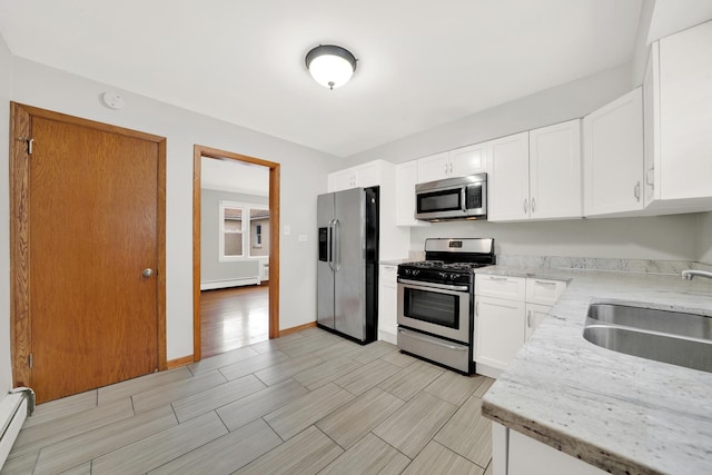 kitchen featuring stainless steel appliances, white cabinetry, a baseboard radiator, and sink