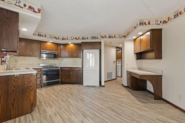 kitchen with sink, electric range, light wood-type flooring, white fridge, and washer / dryer