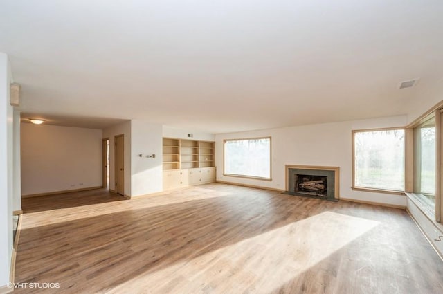 unfurnished living room with built in shelves