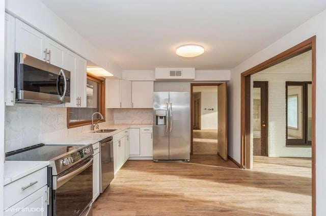 kitchen with decorative backsplash, white cabinetry, sink, and appliances with stainless steel finishes