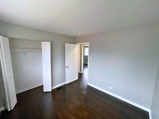 unfurnished bedroom with dark hardwood / wood-style floors and a closet