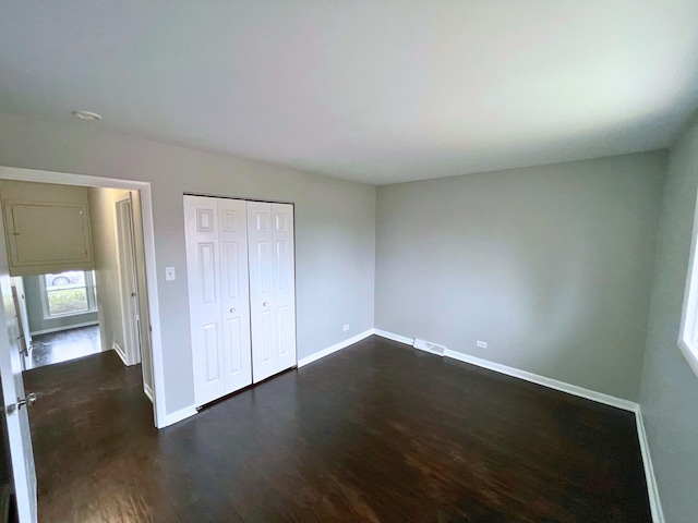 unfurnished bedroom featuring dark hardwood / wood-style flooring and a closet