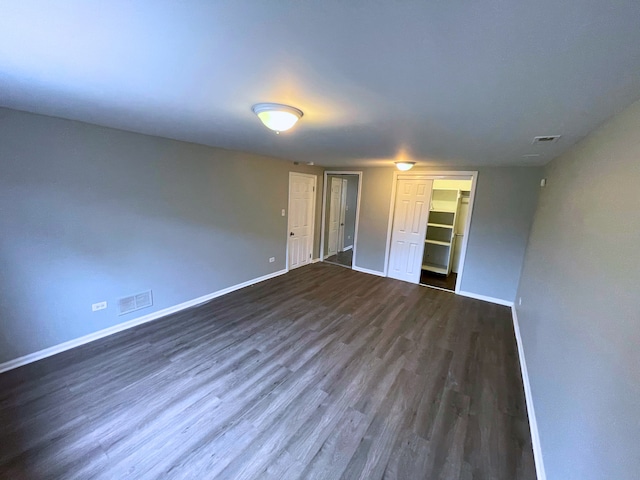 unfurnished bedroom featuring dark hardwood / wood-style flooring, a walk in closet, and a closet