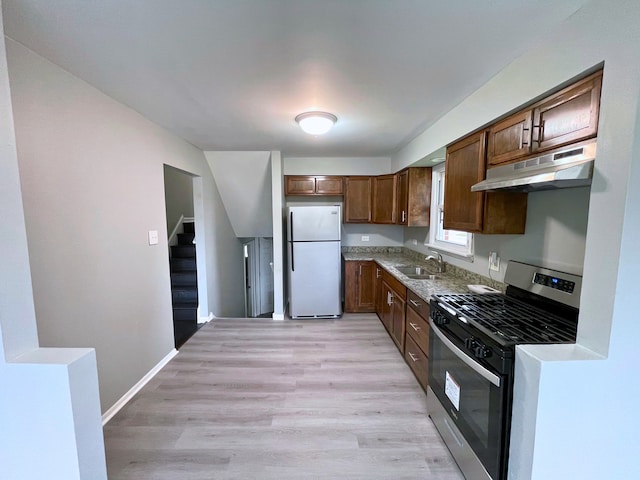 kitchen featuring gas range, light hardwood / wood-style flooring, white fridge, and sink