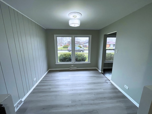 unfurnished dining area with hardwood / wood-style flooring and wooden walls