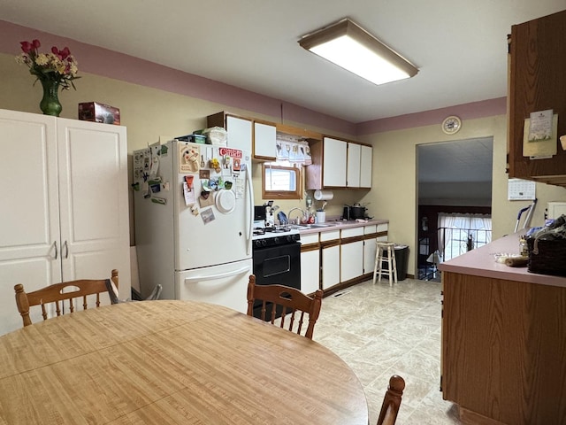 kitchen with white cabinets, white fridge, black range oven, and sink