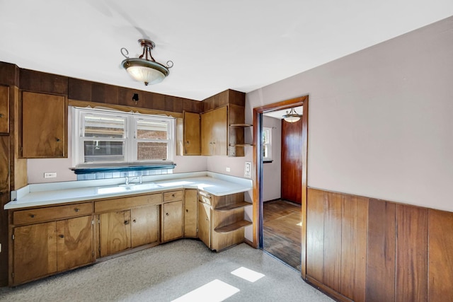 kitchen featuring brown cabinets, open shelves, light countertops, and a sink