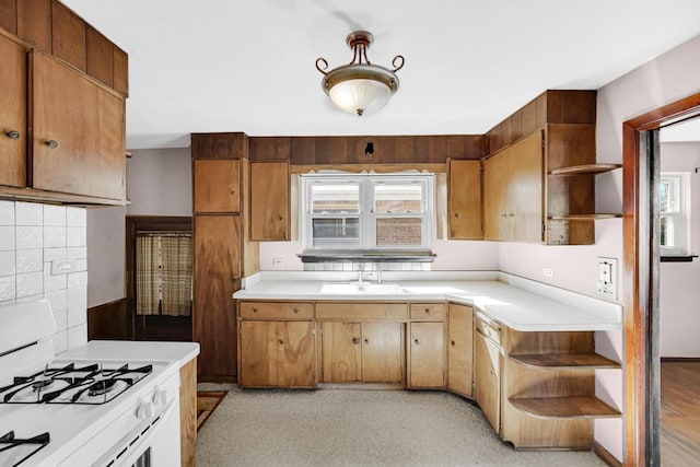 kitchen with open shelves, light countertops, white gas range oven, and a sink