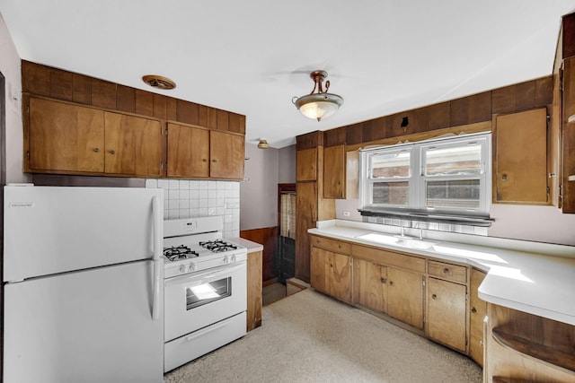 kitchen with white appliances, brown cabinetry, a sink, light countertops, and tasteful backsplash