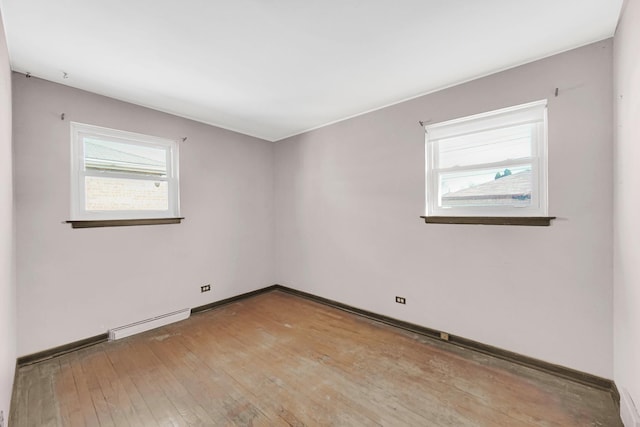 unfurnished room featuring plenty of natural light, baseboards, light wood-type flooring, and baseboard heating