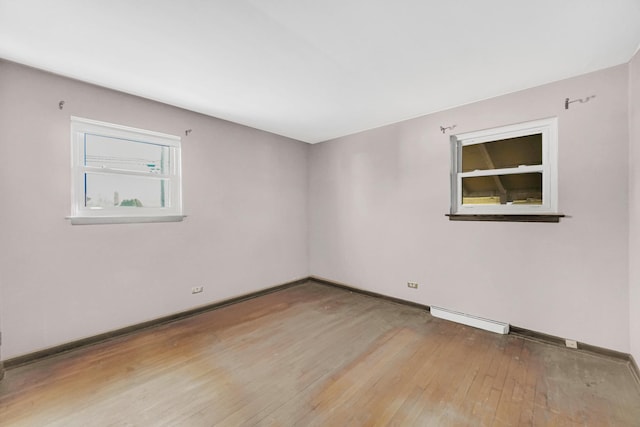 unfurnished room featuring a baseboard radiator, baseboards, and light wood-style flooring