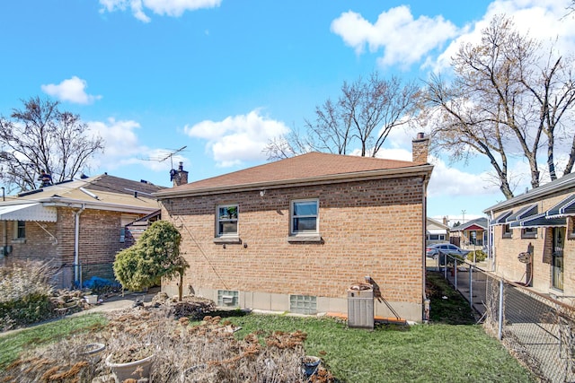 back of property featuring brick siding, a chimney, and fence