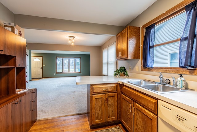 kitchen featuring kitchen peninsula, dishwasher, light colored carpet, and sink