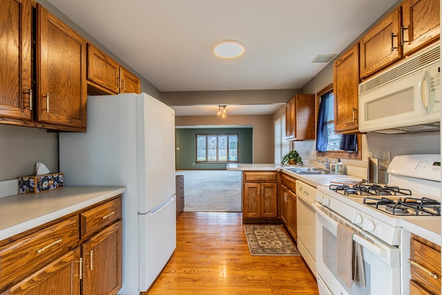 kitchen with kitchen peninsula, light hardwood / wood-style floors, white appliances, and sink