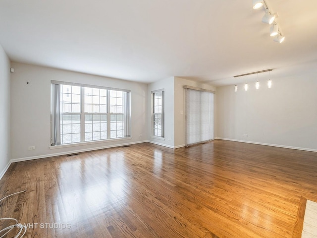 spare room featuring rail lighting and wood-type flooring