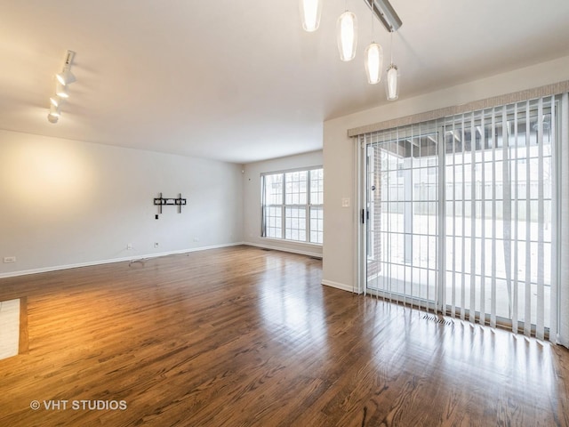 spare room featuring rail lighting and dark wood-type flooring