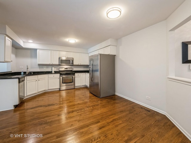 kitchen with dark hardwood / wood-style floors, white cabinetry, sink, and appliances with stainless steel finishes