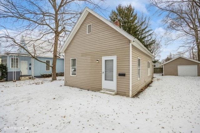 snow covered house featuring an outbuilding and a garage