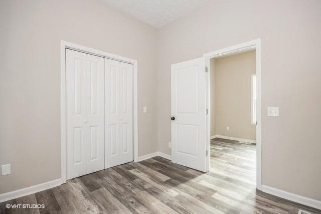 unfurnished bedroom with dark hardwood / wood-style floors, a textured ceiling, and a closet