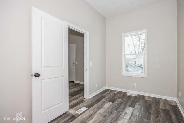 spare room with a textured ceiling and dark hardwood / wood-style floors