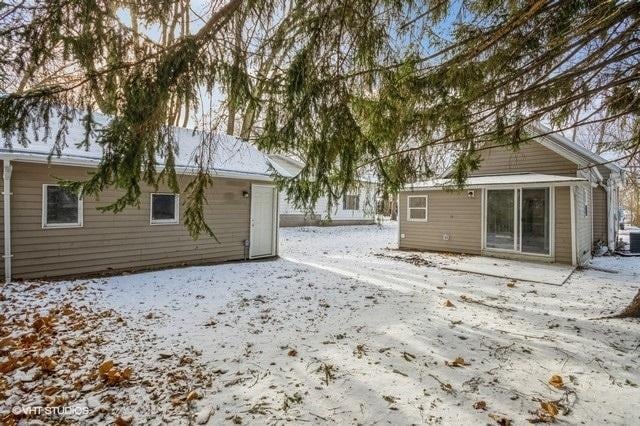 snow covered rear of property featuring central air condition unit