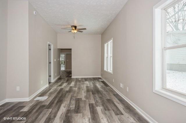 unfurnished room with ceiling fan, dark hardwood / wood-style flooring, a textured ceiling, and a wealth of natural light