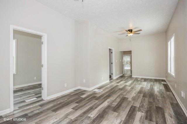 spare room with a textured ceiling, ceiling fan, and dark wood-type flooring