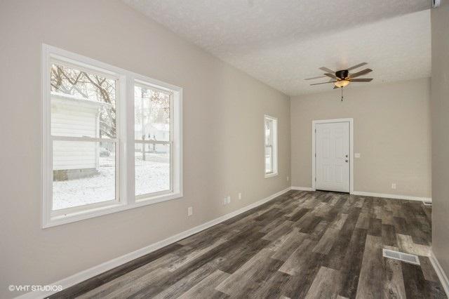 empty room featuring ceiling fan, dark hardwood / wood-style floors, and a textured ceiling