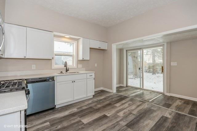 kitchen with dishwasher, sink, dark hardwood / wood-style floors, a textured ceiling, and white cabinets