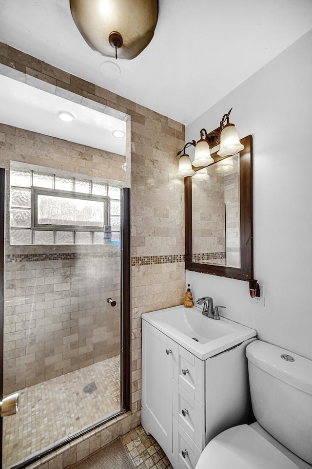 bathroom with an enclosed shower, vanity, tile walls, tile patterned flooring, and toilet